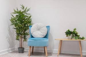 Spital Stay - SJA Stays - Luxury 3 Bed Apartment في أبردين: كرسي ازرق جالس بجانب طاولة فيها نبات