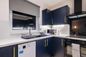 Spital Stay - SJA Stays - Luxury 3 Bed Apartment في أبردين: مطبخ مع دواليب زرقاء ومغسلة