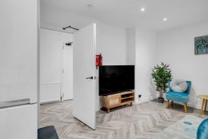 a living room with a tv and a blue chair at Spital Stay - SJA Stays - Luxury 3 Bed Apartment in Aberdeen