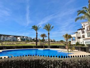 - une piscine bordée de palmiers et de condos dans l'établissement Hacienda Riquelme Golf Resort Fantastic Apartment, à Sucina