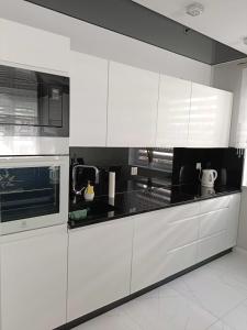 uma cozinha com armários brancos e um forno com placa de fogão em Apartament Zielony Zakątek Wrocław em Breslávia