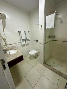 a bathroom with a toilet and a glass shower at Art Hotel in Tubarão