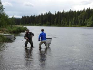 dos hombres están parados en el agua en un río en Rena Hostel, en Rena