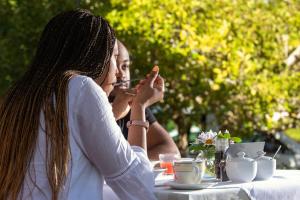 una mujer está sentada en una mesa comiendo comida en Bonne Esperance Boutique Guest House, en Stellenbosch