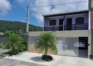 a house with a gate and palm trees in front of it at Residencial Caiobá I in Matinhos