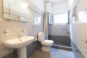 bagno con lavandino, servizi igienici e finestra di Nikos Cassiopeia a Kassiopi