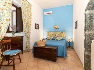 1 dormitorio azul con 1 cama y 1 silla en Casa Vacanza La Fontanella, en Piedimonte Etneo