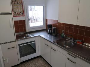 a kitchen with white cabinets and a sink and a window at Holiday Home Peisel by Interhome in Disentis