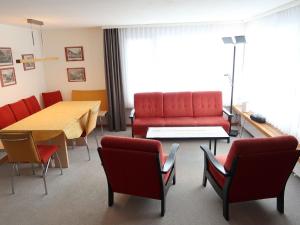 a waiting room with a red couch and chairs at Holiday Home Peisel by Interhome in Disentis