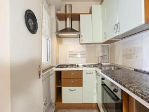 Una cocina con gabinetes blancos y un reloj en la pared. en Apartment Fulvia by Interhome, en Santo Stefano al Mare