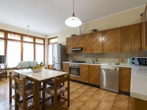 una cocina con armarios de madera y una mesa con sillas. en Holiday Home Irma by Interhome, en Cipressa
