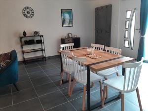 jadalnia z drewnianym stołem i białymi krzesłami w obiekcie Mulots et Bulots w mieście Saint-Hilaire-Petitville