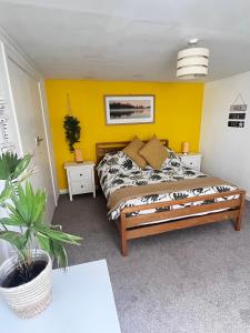 a bedroom with a bed with a yellow wall at Jasper Apartment in Lyme Regis