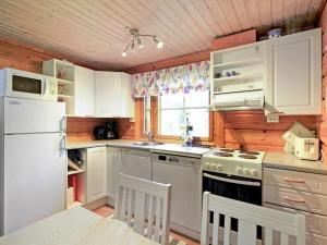 a kitchen with white cabinets and a white refrigerator at Holiday Home Marjatan mökki by Interhome in Ylikyro