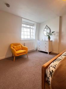 a bedroom with a bed and a chair and a dresser at Jasper Apartment in Lyme Regis