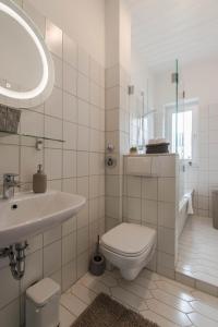 Baño blanco con aseo y lavamanos en Business Apartment, en Wiesbaden