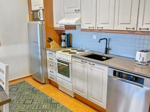 a kitchen with white cabinets and a sink and a refrigerator at Holiday Home Aquahovi b5 by Interhome in Sirkka