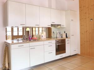 a white kitchen with white cabinets and appliances at Apartment Haus Lohnerblick by Interhome in Kandersteg