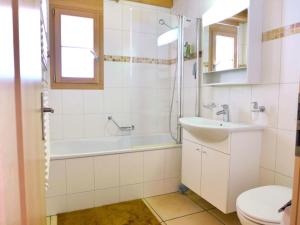 ein Badezimmer mit einer Badewanne, einem Waschbecken und einem WC in der Unterkunft Apartment Haus Lohnerblick by Interhome in Kandersteg