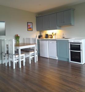 a kitchen with white cabinets and a table and chairs at Hilltop Haven, Doolin in Doolin