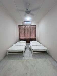 dwa łóżka w pokoju z oknem w obiekcie Dagang Homestay w mieście Ampang