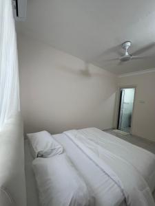 a white bed with white sheets and a ceiling at Dagang Homestay in Ampang