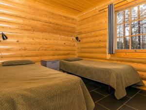 Holiday Home Villa assi by Interhome في Haapamäki: سريرين في غرفة بجدران خشبية
