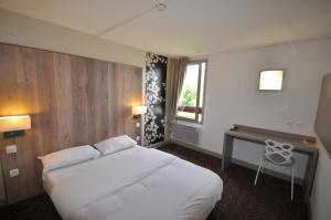 een hotelkamer met een groot wit bed en een bureau bij The Originals City, Hôtel Mulhouse Est in Rixheim