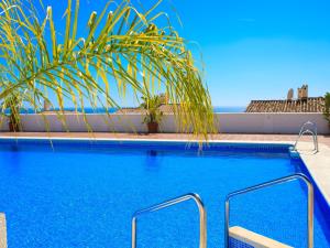 a swimming pool with blue water and a palm tree at Villa Las Brisas by Interhome in Nerja