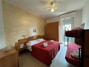 una camera d'albergo con un letto con una coperta rossa di Hotel Caruso a Rimini