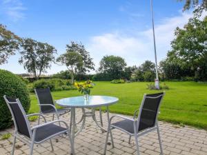 una mesa con sillas y un jarrón de flores en el patio en Holiday Home Ulv - 20km from the sea in Western Jutland by Interhome, en Ribe