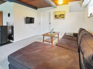 ein Wohnzimmer mit einem braunen Sofa und einem Tisch in der Unterkunft Holiday Home Ulv - 20km from the sea in Western Jutland by Interhome in Ribe