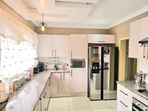 a kitchen with white cabinets and a refrigerator at Downham Views in Johannesburg