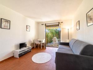 ein Wohnzimmer mit einem Sofa, einem TV und einem Tisch in der Unterkunft Studio Les Mas de Pramousquier-12 by Interhome in Le Lavandou