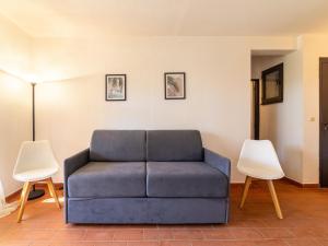 eine blaue Couch in einem Wohnzimmer mit zwei Stühlen in der Unterkunft Studio Les Mas de Pramousquier-12 by Interhome in Le Lavandou