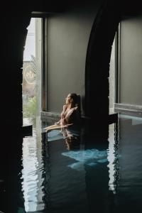 a woman sitting on a window sill in the water at NINE DOTS Azorean Art Boutique Hotel in Ponta Delgada