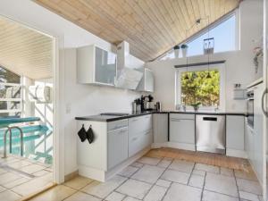 cocina con armarios blancos y ventana grande en Holiday Home Ehlin - 150m from the sea in NE Jutland by Interhome, en Saeby