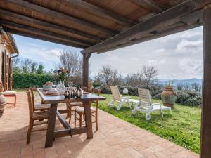 une terrasse avec une table en bois et des chaises sur la pelouse. dans l'établissement Holiday Home Elena by Interhome, à Sassofortino