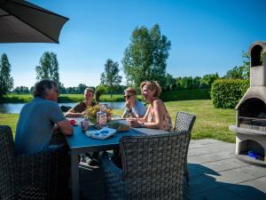 a group of people sitting at a picnic table at Holiday Home Vrieschehuis Comfort Royaal by Interhome in Vlagtwedde