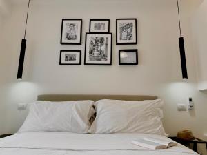 a bedroom with a white bed with four pictures on the wall at Room Center Sorrento Baby in Sorrento