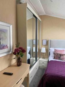 ein Schlafzimmer mit einem Bett und einem Schreibtisch mit Blumen darauf in der Unterkunft Hot Tub Lodge with Panoramic Views & Free Golf in Swarland