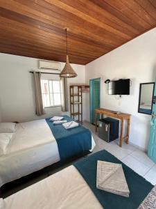 um quarto com uma cama, uma secretária e uma televisão em Jambo 1 em Marau