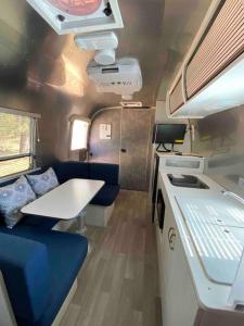 un interior de una caravana con una mesa y asientos azules en Modern Airstream with amazing view - 10 to 15 minutes from Kings Canyon National Park, en Dunlap