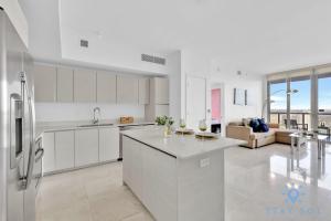 een keuken met witte kasten en een woonkamer bij Breathtaking 31st Fl Beachwalk Penthouse View in Hallandale Beach