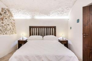 um quarto com uma grande cama branca com duas mesas de cabeceira em La casa del '600 Holiday House Amalfi Coast em Amalfi