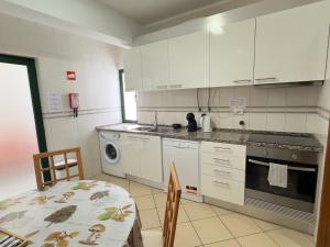 kuchnia z białymi szafkami, stołem i kuchenką w obiekcie Apartamento Canaima w mieście Quarteira