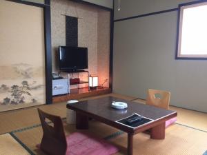 a living room with a table and a tv at Yuzawa Hotel in Yuzawa