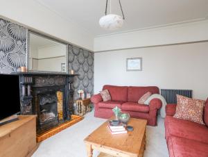 Llwyn Onn في كريسيث: غرفة معيشة مع أريكة حمراء ومدفأة