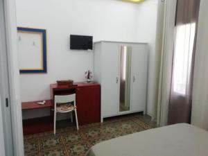 トラーパニにあるSAT Appartamenti Locazioni turistiche brevi-G&P HOLIDAY HOMEのベッド、デスク、冷蔵庫が備わる客室です。