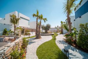 a walkway with palm trees and a building at Nas House Private & Shared Villas in Dubai